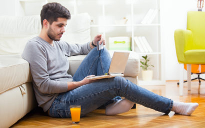 Man sitting on floor with computer and credit card in hand