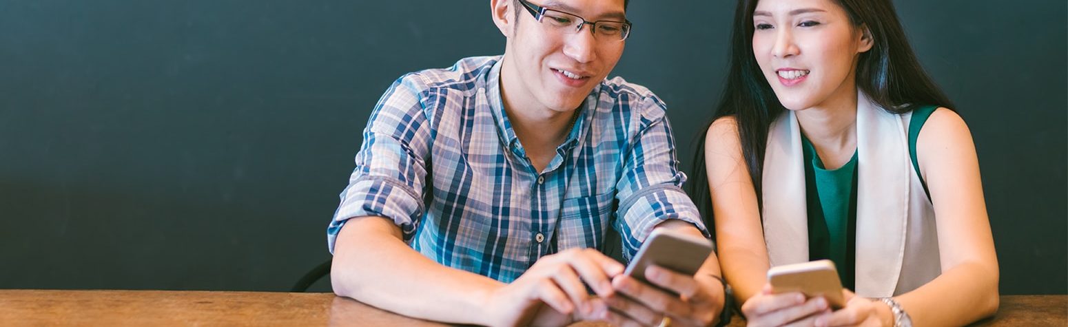 two smiling people looking at cell phone