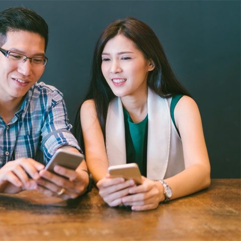 two smiling people looking at cell phone