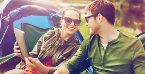 Couple smiling outside using tablet device