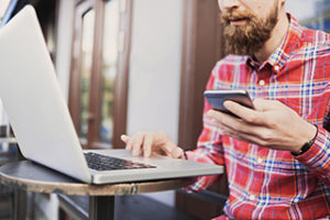 Young man using smart phone and laptop computer