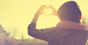 woman holding up a heart symbol