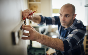 A man making measurements on a wall with a carpenter's ruler and a pencil