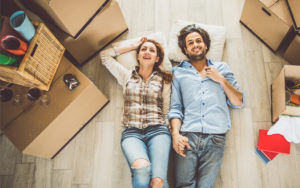 Couple laying the a floor with moving boxes around them.