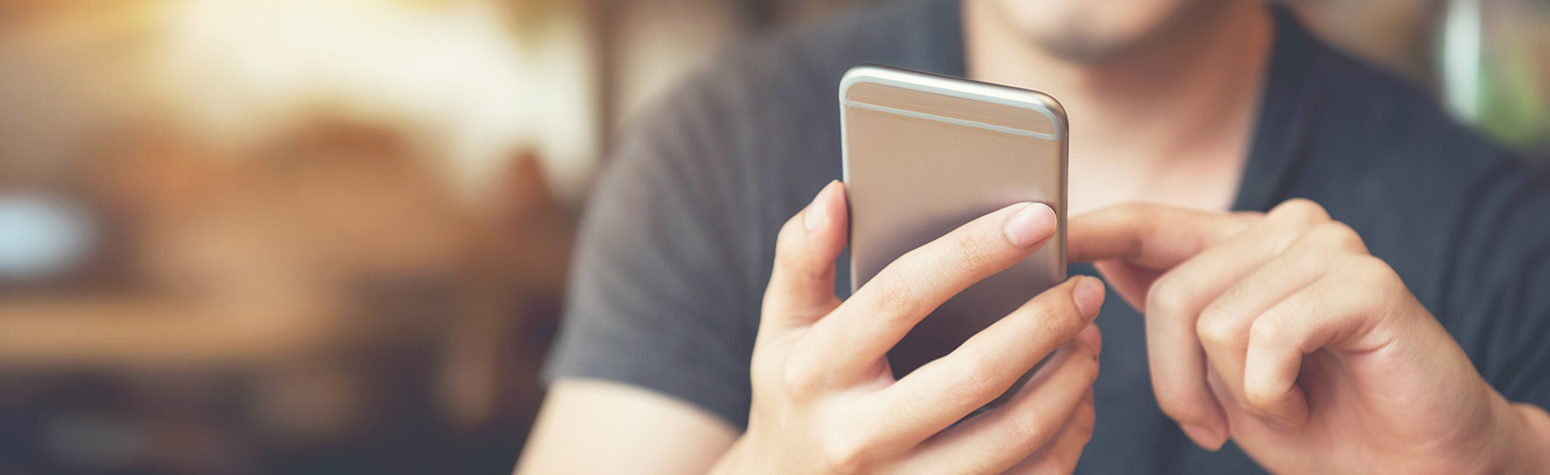 Young man sitting at a table looking at his cell phone in his hand