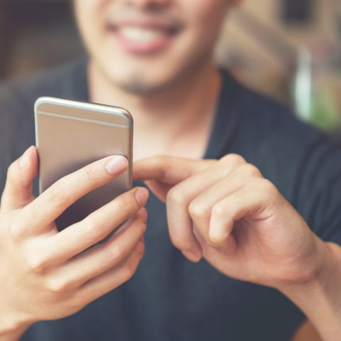 Young man sitting at a table looking at his cell phone in his hand