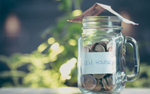Mason jar sitting on a table with coins inside and a dollar on top of jar.