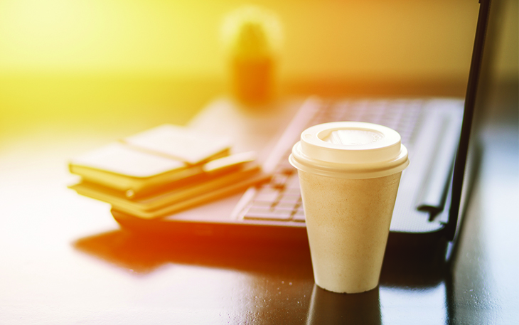 To go coffee cup next to a computer