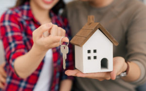 Couple with keys in hand and a small home in hand