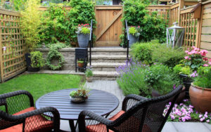 Backyard with a table and two chairs facing a fence door with stairs