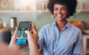 Woman standing at a counter while another woman's hands are showing her completing a credit card transaction.