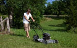 Teenage boy is mowing the lawn.