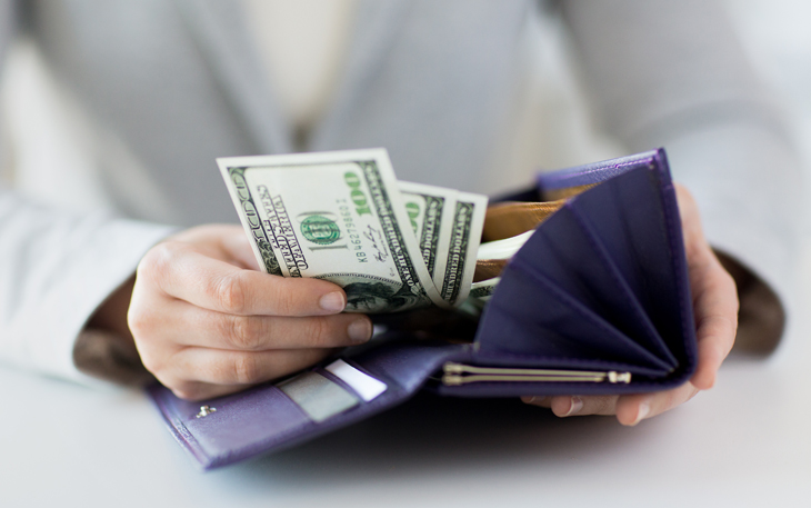 A woman puts $300 in her wallet