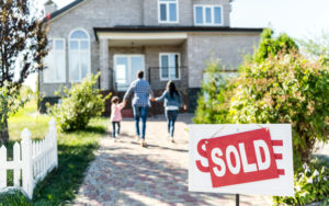 Daughter, dad and mom walk hand-in-hand towards their newly purchased home.