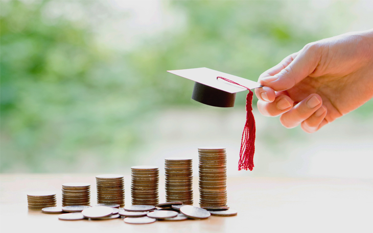 Stack of coins with a graduation cap being placed on the highest stack.