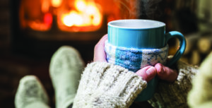 Warming up with blue coffee cup in hand next to a fire