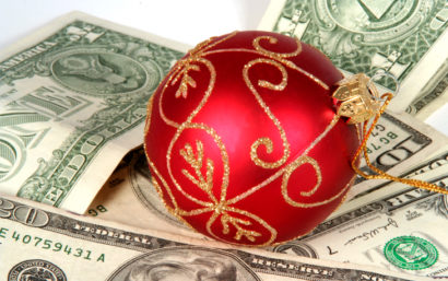 A red holiday tree bulb sits on top of cash.