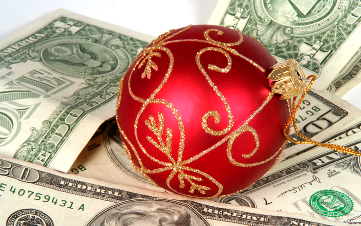 A red holiday tree bulb sits on top of cash.