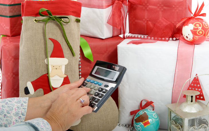 Woman uses calculator in front of Christmas gifts