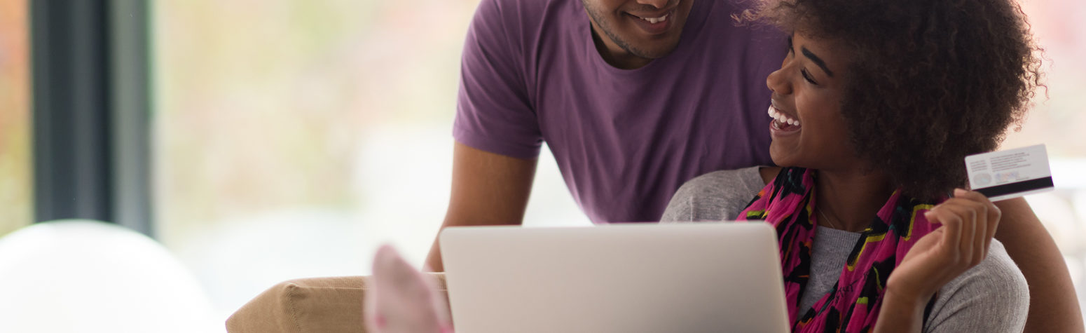 Couple on couch with laptop paying with their SouthPoint Credit Card