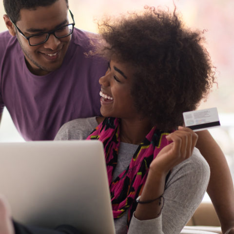 Couple on couch with laptop paying with their SouthPoint Credit Card