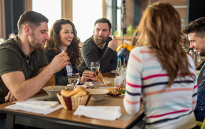 Group of friends at a restaurant talking and eating pizza.