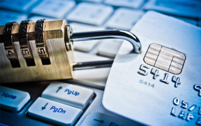 A credit card has a dial lock attached to it. Credit card lays on top of a keyboard.