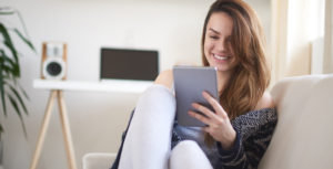Young lady sitting on couch with tablet in hand using VideoConnect through SouthPoint