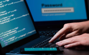 Close-up of hands on a computer as someone hacks into a computer system.