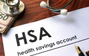 Stethoscope sits on top of cash with a sheet displaying the words HSA