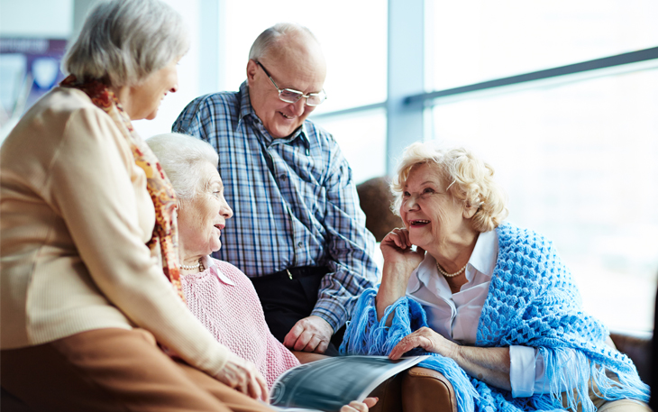 Group of elderly men and women talk with each other and laugh.