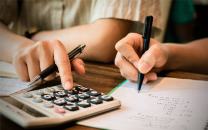 Close up of hands writing and using calculator