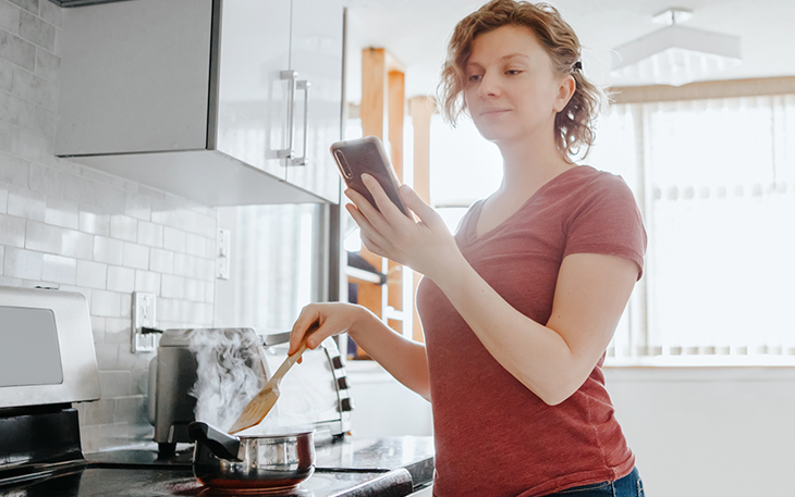 Lady looking her cell phone while cooking