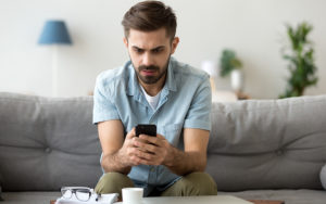 Man looking at phone on his couch