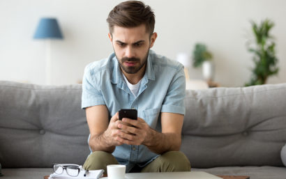 Man looking at phone on his couch