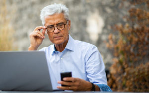 Older man on his computer and looking at his phone