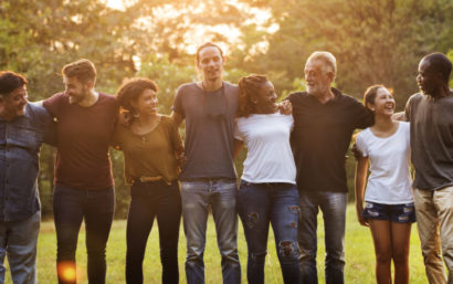 Group of individuals standing outside looking happy.