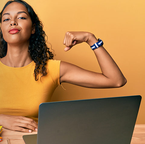 Woman flexing arm in front of computer and calculator