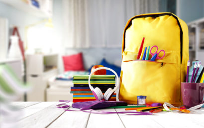 School backpack with supplies on table