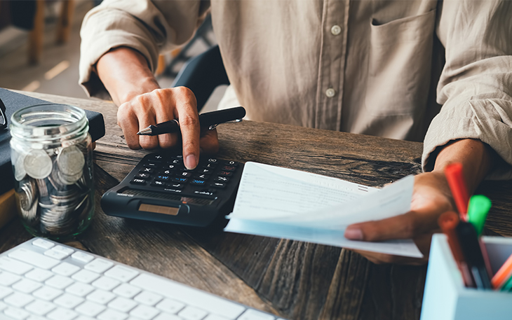 Person balances checkbook with calculator