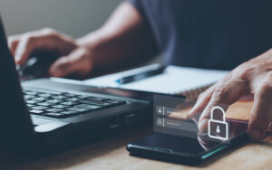 Person using a computer and phone. Phone has lock-screen image.